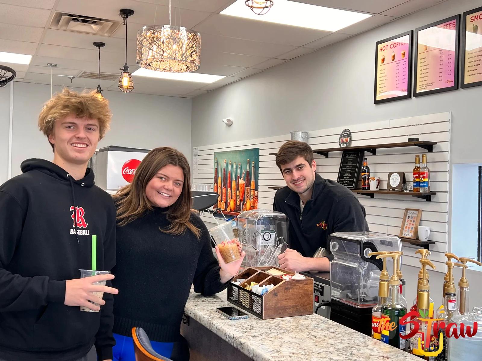 Three smiling people sharing a drink run at The Straw counter